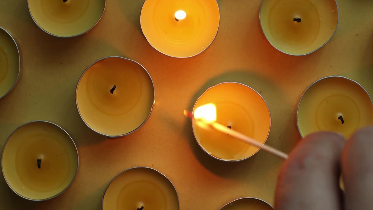 Yellow tea candles on an orange background, close-up, top view of the turntable, romantic pattern.
