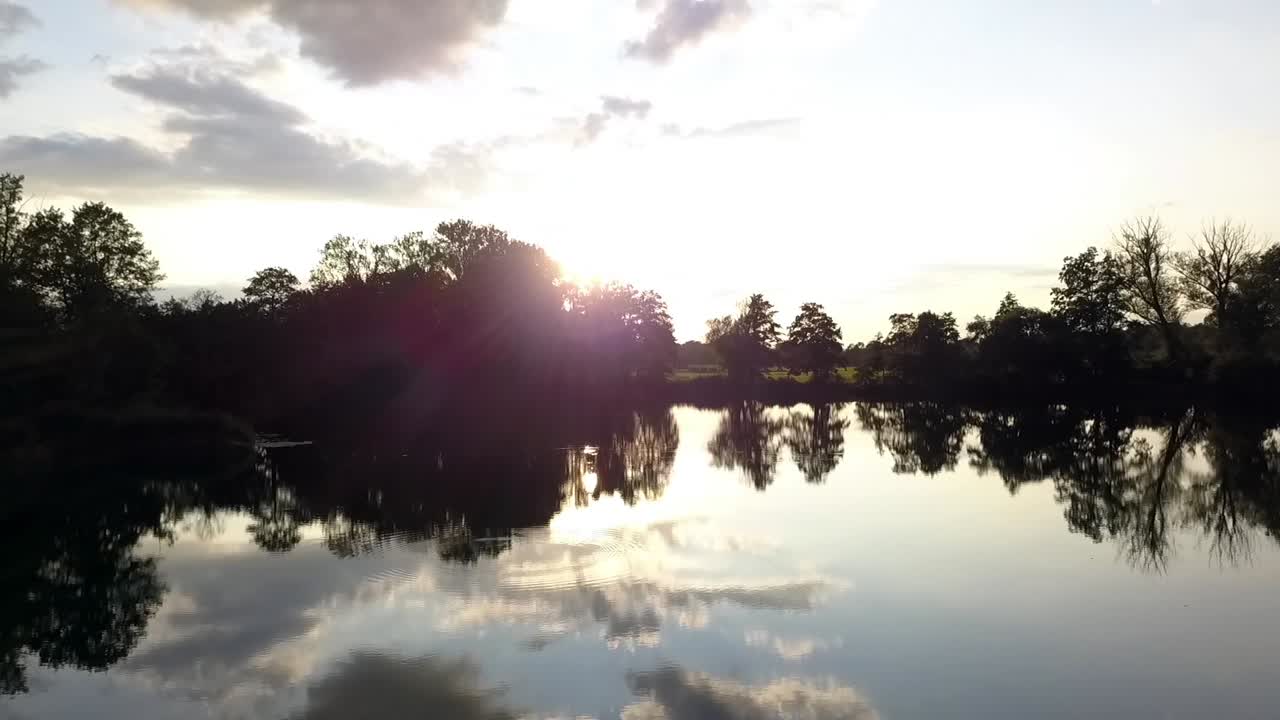 Buttery soft aerial flight fly forwards drone shot over a lake clouds and sky are mirroring