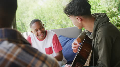diversos amigos adolescentes felices tocando la guitarra en casa, en cámara lenta