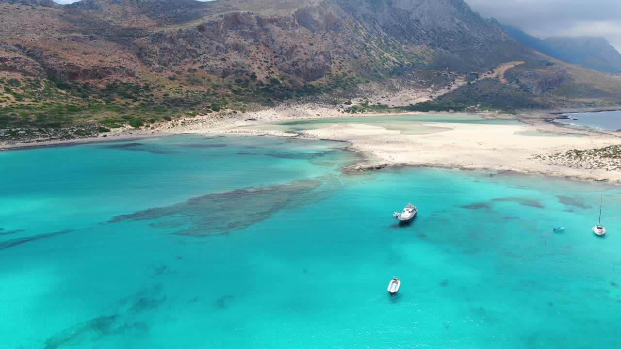 Balos Beach in Crete Greece with  turquoise waters and a tourist transport ship and it's dinghy boat attached, Aerial flyover reveal shot