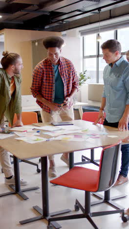 vertical video of happy diverse business people discussing work in office in slow motion