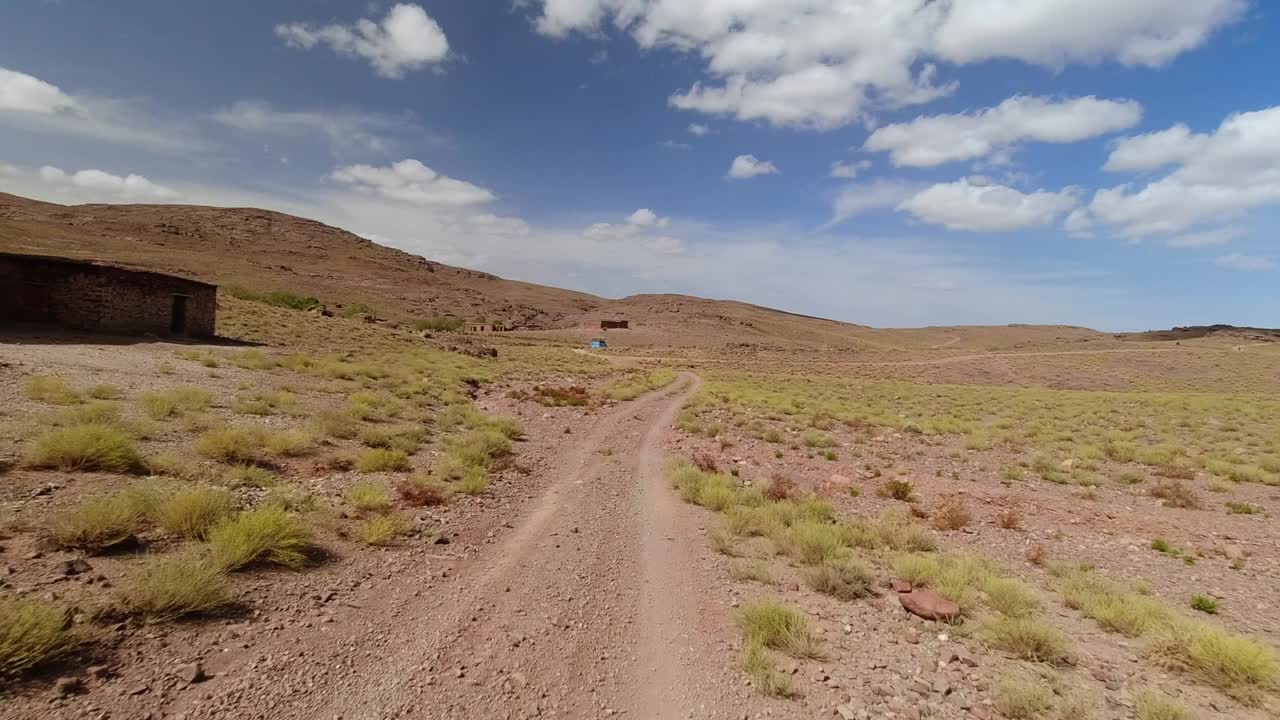 punto de vista de un conductor que pasa junto a una escuela solitaria en las desérticas montañas del alto atlas en marruecos