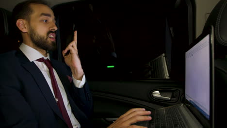 Successful-businessman-working-on-his-laptop-in-the-back-seat-of-his-limousine