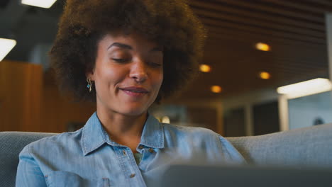 Close-Up-Of-Businesswoman-In-Modern-Open-Plan-Office-Working-On-Laptop-In-Casual-Seating-Area