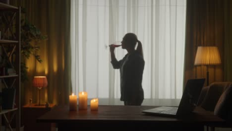 woman drinking wine by the window at home