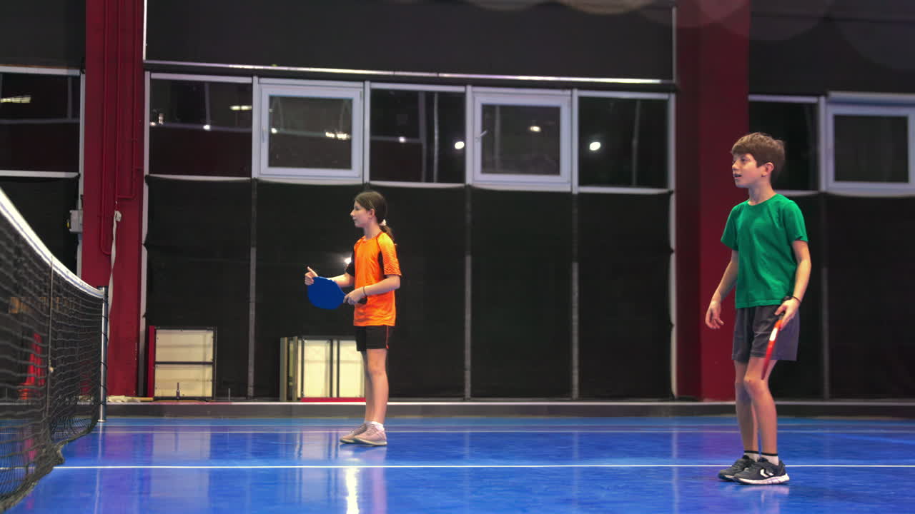 A man in a yellow t-shirt posing after playing pickleball on a blue, inside court