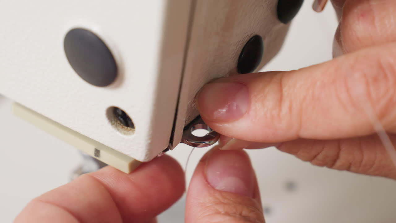 Hand of female creative skillfully adjusting robe on sewing machine, highlighting manual process, bright environment, and close up perspective focusing on tension for secure finishing