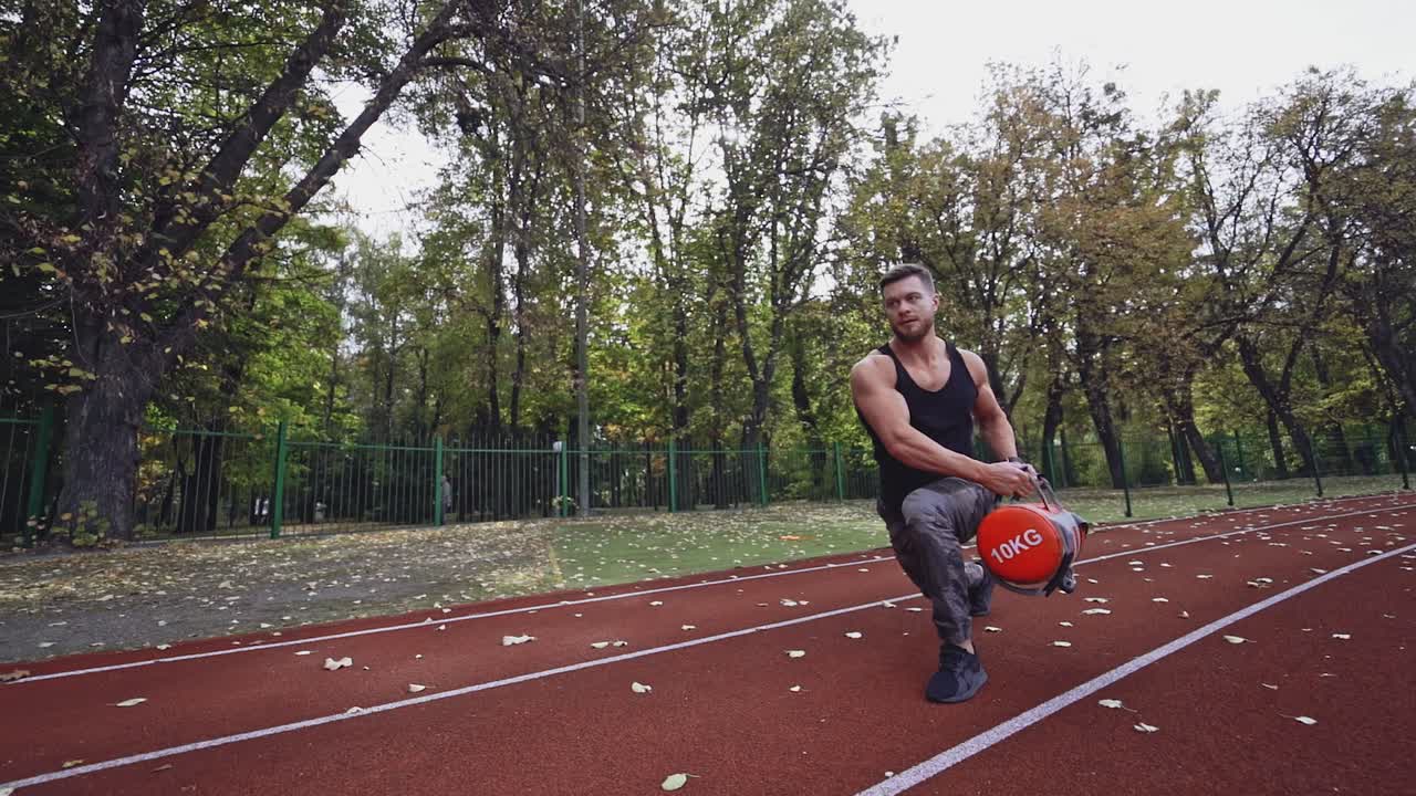 Fitness man exercises outdoors in autumn. Healthy sportsman training his muscular body with weight in the modern stadium.