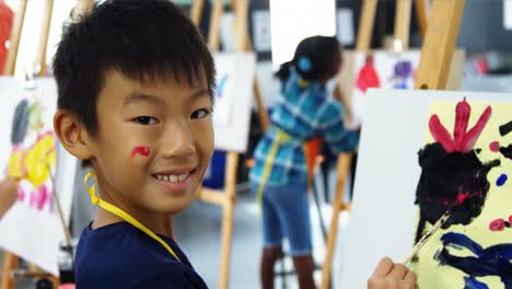 Portrait-of-schoolboy-panting-on-canvas-during-drawing-class