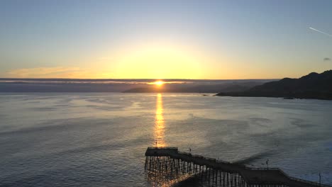 sunset over calm sea with pismo beach pier in california, usa. - aerial