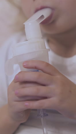 little girl with bronchitis undergoes procedure with inhaler lying in comfortable bed in light room extreme close view