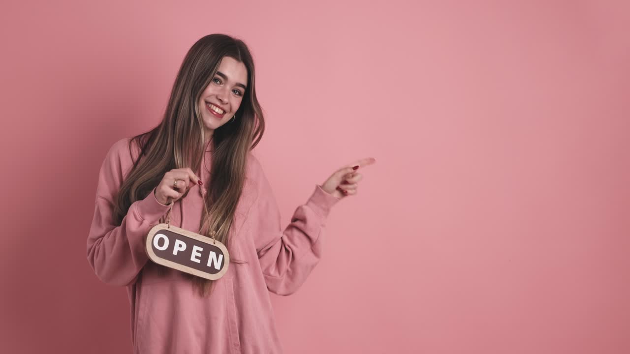Cheerful young woman standing and carrying open signboard