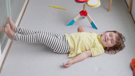 niña coreano-ucraniana acostada en el suelo cerca de sus juguetes sonriendo a la cámara