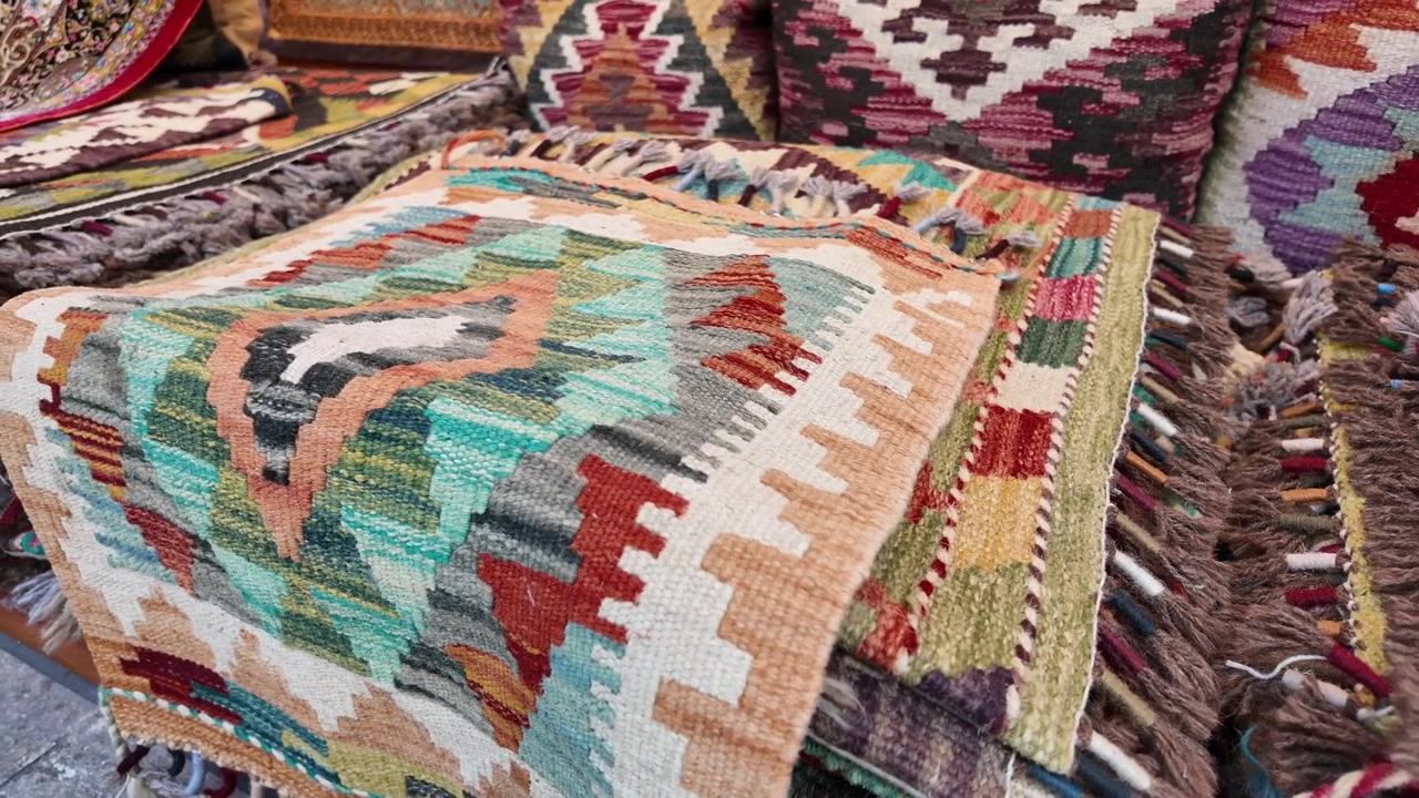 Pila di tappeti Kilim e cuscini colorati tessuti a mano