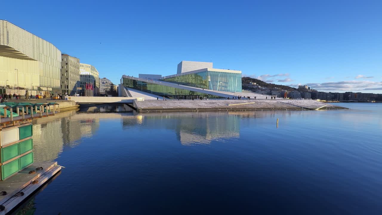Oslo Opera House Norway Norge winter OsloFjord afternoon early sunset arctic sun clear skies tourist attraction people walking calm sea birds Oslo Library Munch sauna buildings pan left motion