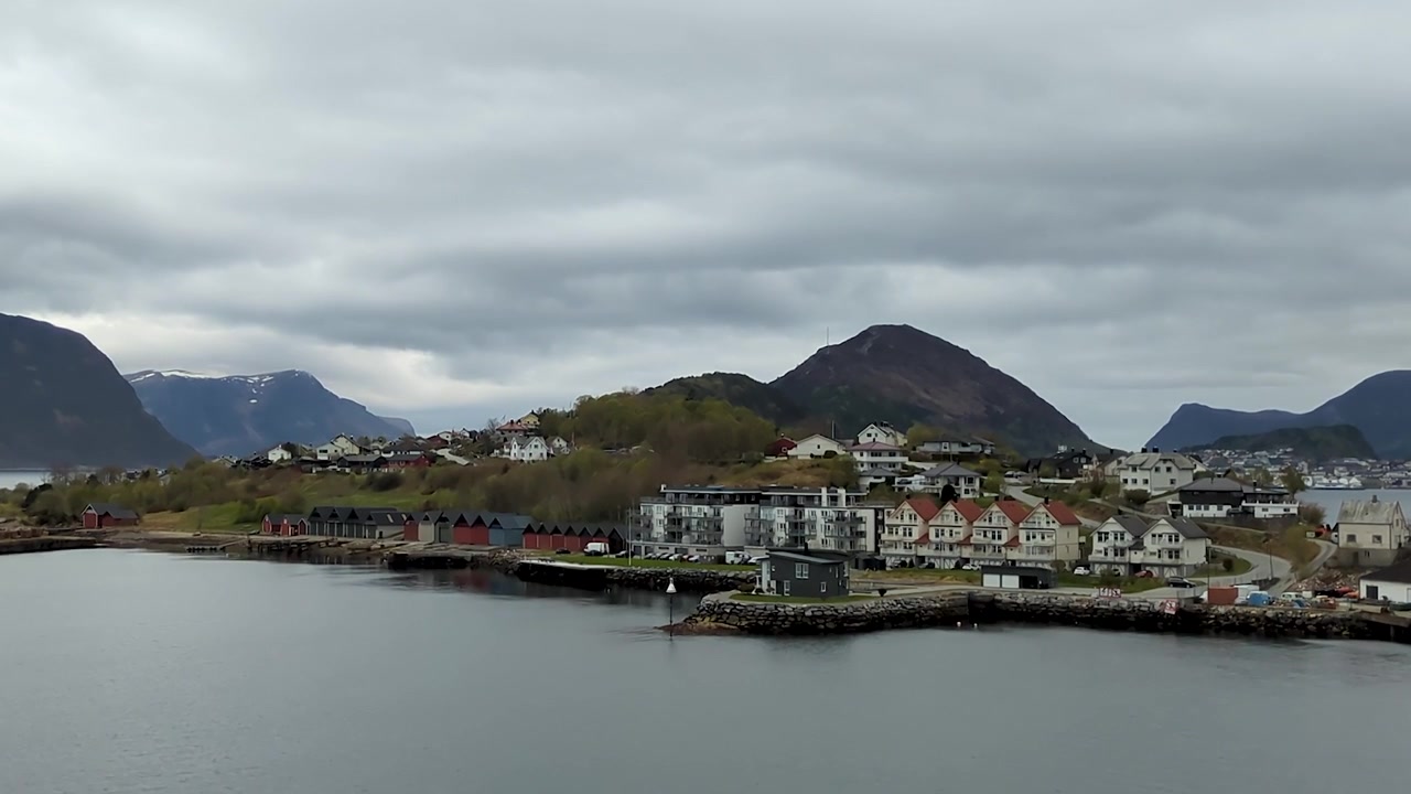 Ålesunds havnefront med bådhuse, huse på bjergsiderne og sneklædte bjerge, Norge