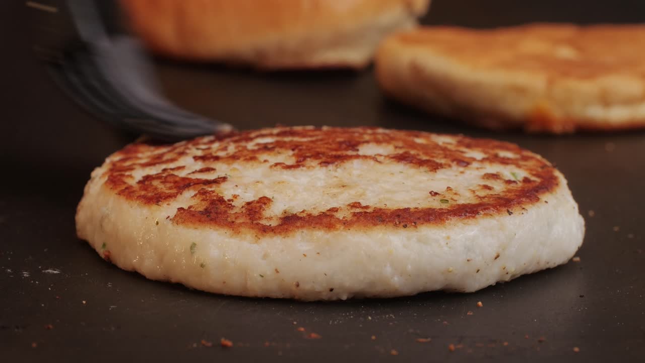 Cooking American fat smash burger on grill close-up. Chiken or fish cutlet smashing by burger press. The chef in kitchen of the restaurant making cutlets for burgers - smash burger beefsteak. Fast and street food concept. High quality 4k footage