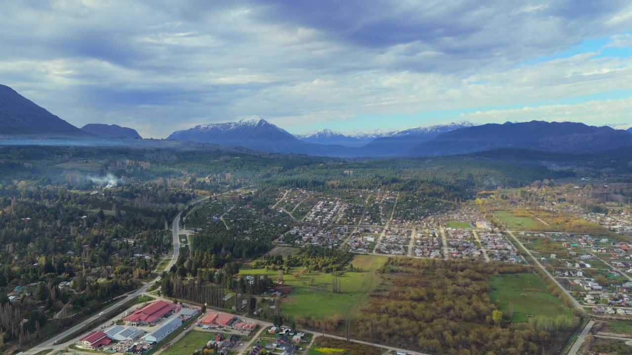 Incantevole città di El Bolson, immersa nel verde lussureggiante e circondata dalle maestose Ande con la cima Piltriquitron in Patagonia, provincia di Rio Negro, Argentina. Ripresa drone di presentazione.