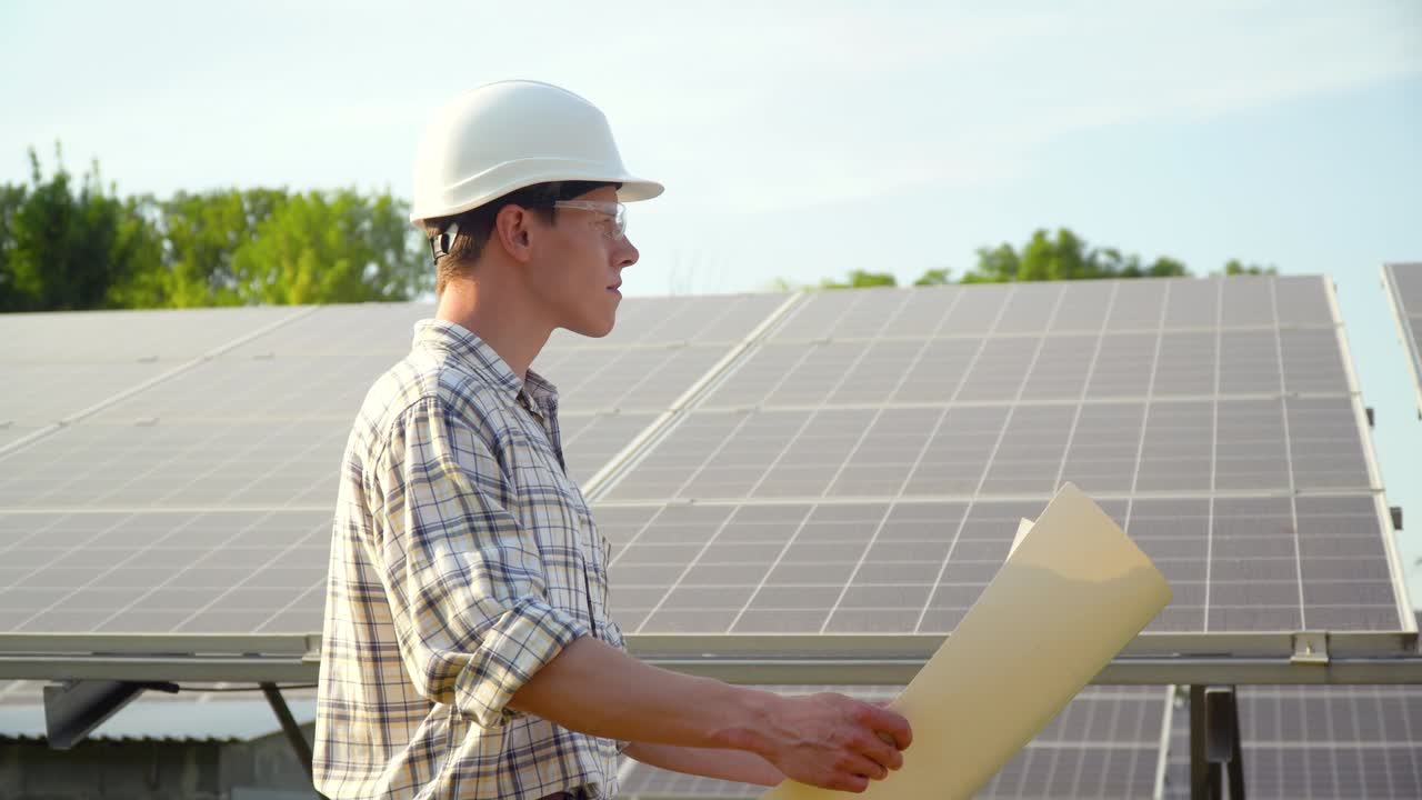 Young enginneer installing new sunny batteries. Worker in a hardhat installing photovoltaic panels on a solar farm