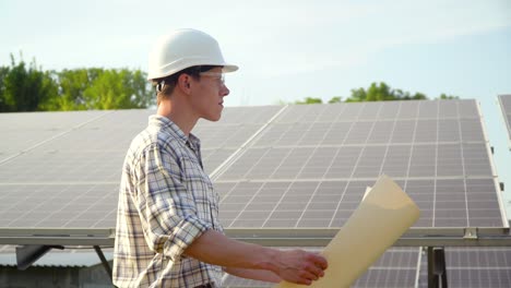 young enginneer installing new sunny batteries. worker in a hardhat installing photovoltaic panels on a solar farm