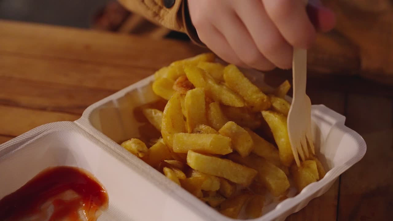 en el festival, la gente disfruta de una caja de poliestireno de papas fritas y salsa de tomate.