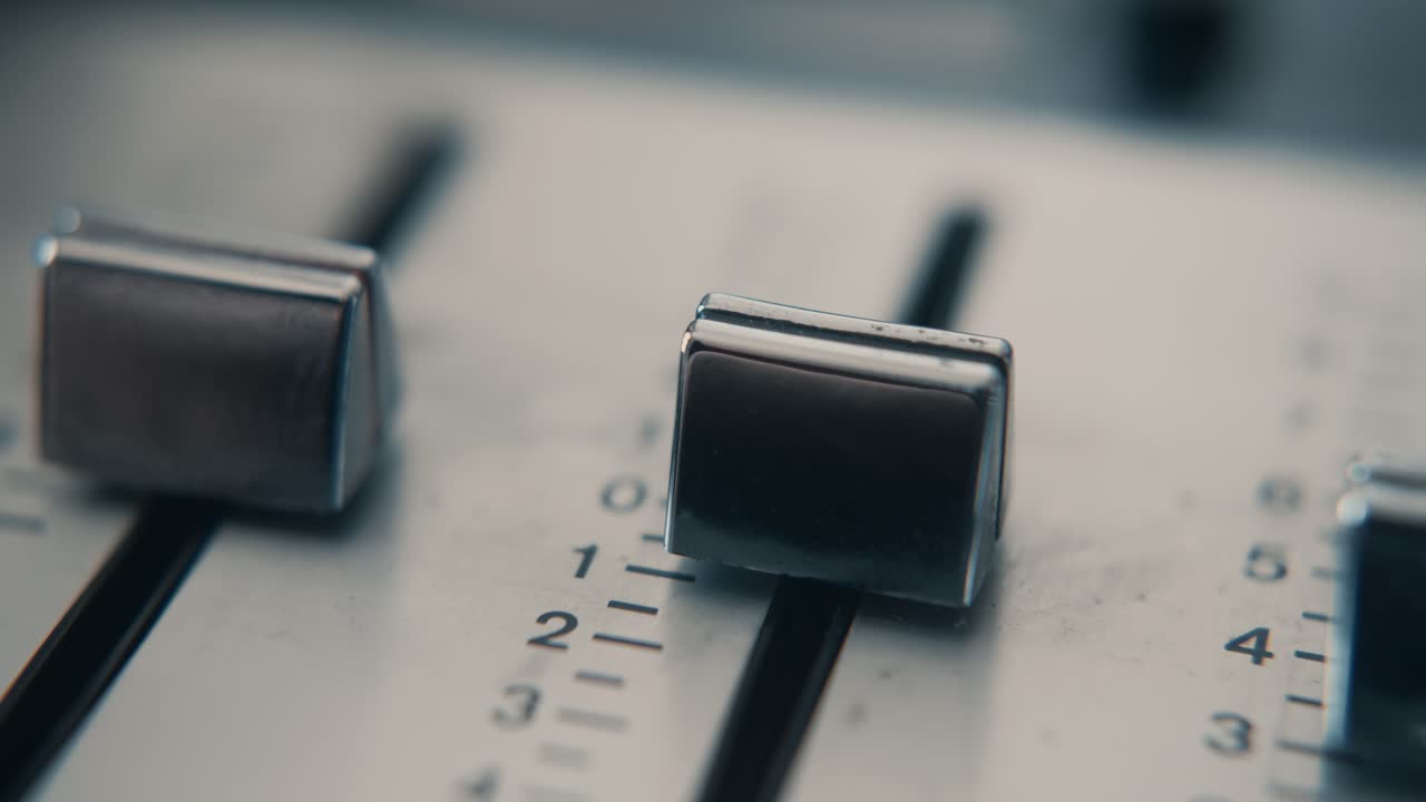 Close-up of Finger Adjusting Faders on Audio Mixer