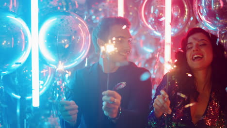 Excited-man-and-woman-holding-lights-in-club.-Couple-celebrating-under-confetti