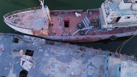 4k drone view of derelict rusted vessels docked in still water. great for maritime, industrial decay, or environmental stock projects. perfect texture and symmetry for visual storytelling.