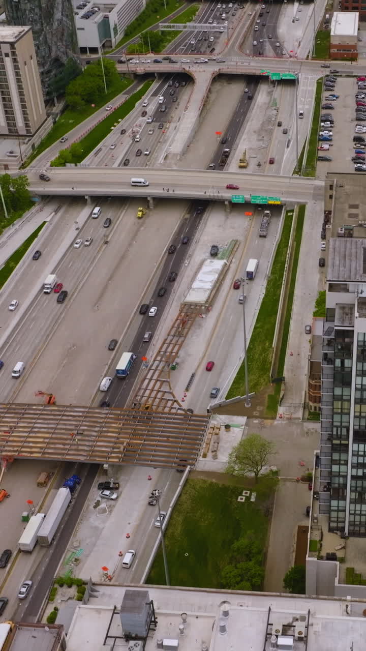 Multiple busy roads with lots of cars on crossing the downtown of contemporary Chicago. Huge parking lots full of cars nearby multi-storied buildings. Top view. Vertical video
