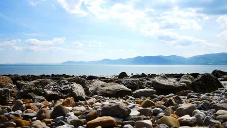 colourful variety of stone boulders beach landscape under north wales mountain range rise jib left shot