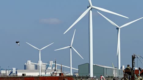 wind turbines turning on the dock side of a port with and ship docked in harbor