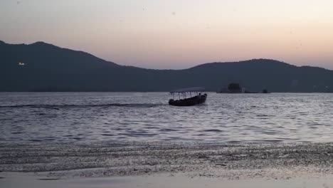 Silhouette-of-traditional-Vietnam-boat-sailing-out-in-early-morning,-static-view