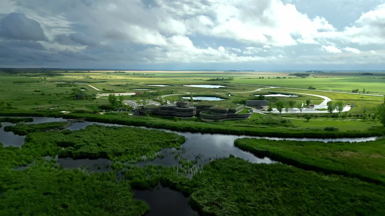 Sunbeams break through clouds over eco centre amid summer marshland