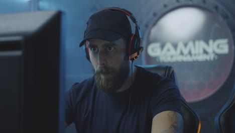 happy young man finishing playing video game and celebrating winning tilt up view of happy caucasian young man finishing playing video game and celebrating winning while sitting in gaming chair in front of computer monitor
