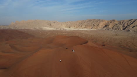 uae desert:  top view of sharjah desert, a group of 4x4 vehicles, rides on giant sand dunes, mleiha mountains in the background. 4k footage