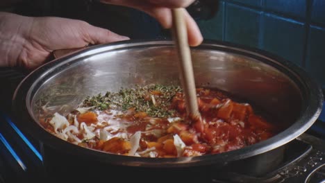cuchara de madera que se usa para revolver las verduras picadas en una olla en la cocina con la tapa colocada encima para dejar que se guise