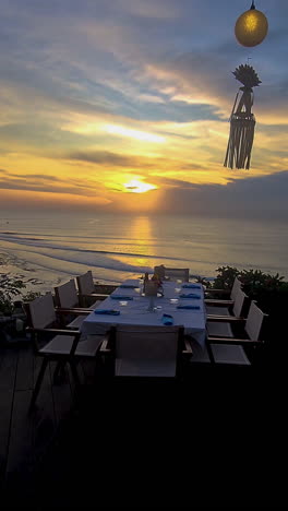 vertical view of sunset on bali island and dining table dinner settings