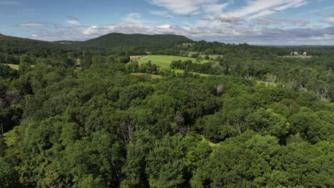 A-high-angle,-aerial-view-of-the-hills-and-valleys-of-Salisbury-Mills,-NY-on-a-beautiful-and-sunny-day-with-blue-skies-and-white-clouds