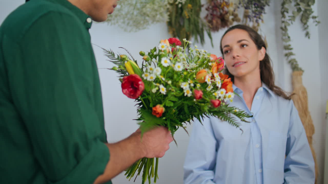 Donna felice che vende fiori primaverili. Il fidanzato annusa e compra un bouquet