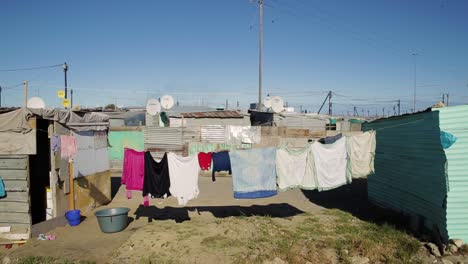 an informal settlement in cape town, south africa. people live in poverty in shacks. there is a washing line in the foreground.