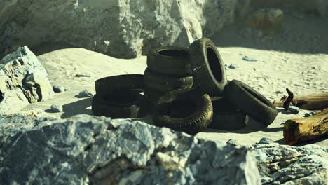 discarded tires clutter sandy beach under sunlight in serene natural setting