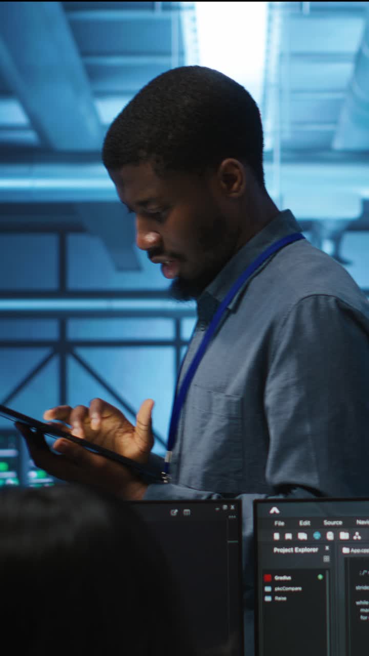 African American Man Using Tablet in Server Room with Code