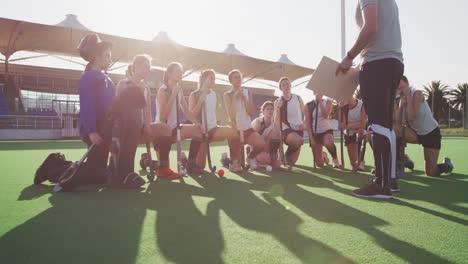 hockey coach explaining game plan with female players on the field