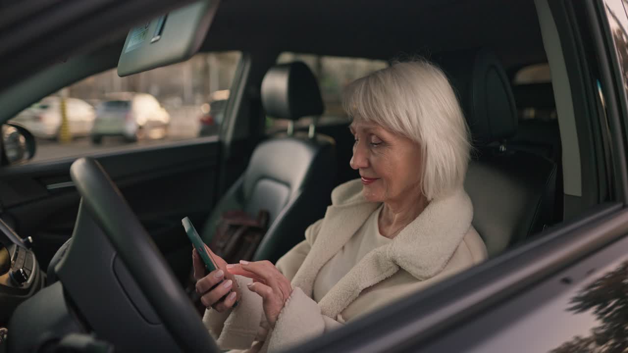 Senior woman using smartphone in her car