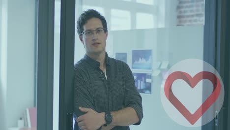 icono de corazón sobre estandarte redondo contra el retrato de un hombre caucásico con los brazos cruzados sonriendo en la oficina