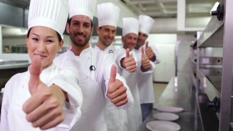 chefs sonrientes de pie en una fila dando pulgares hacia arriba