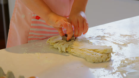 mid section of little girl preparing cookie from dough in kitchen of comfortable home 4k