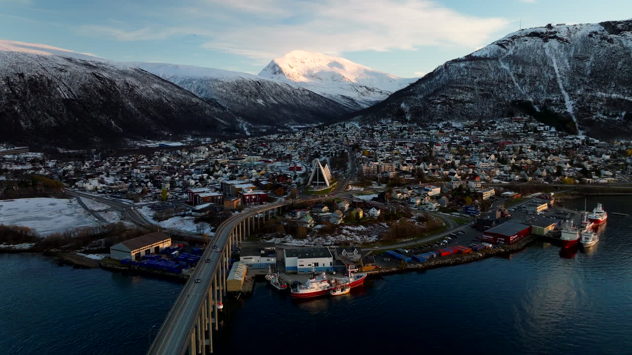 Vue aérienne de la ville de Tromsø recouverte d’une légère neige hivernale, avec circulation sur le pont