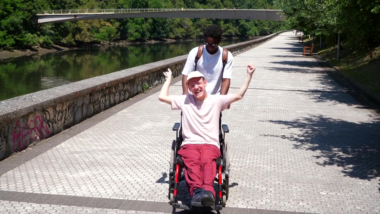 Two Friends Having Fun Outdoors with a Wheelchair