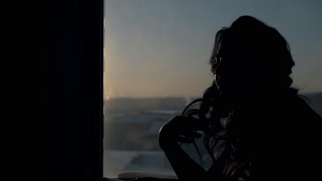 girl straightens hair with hands at large window side view